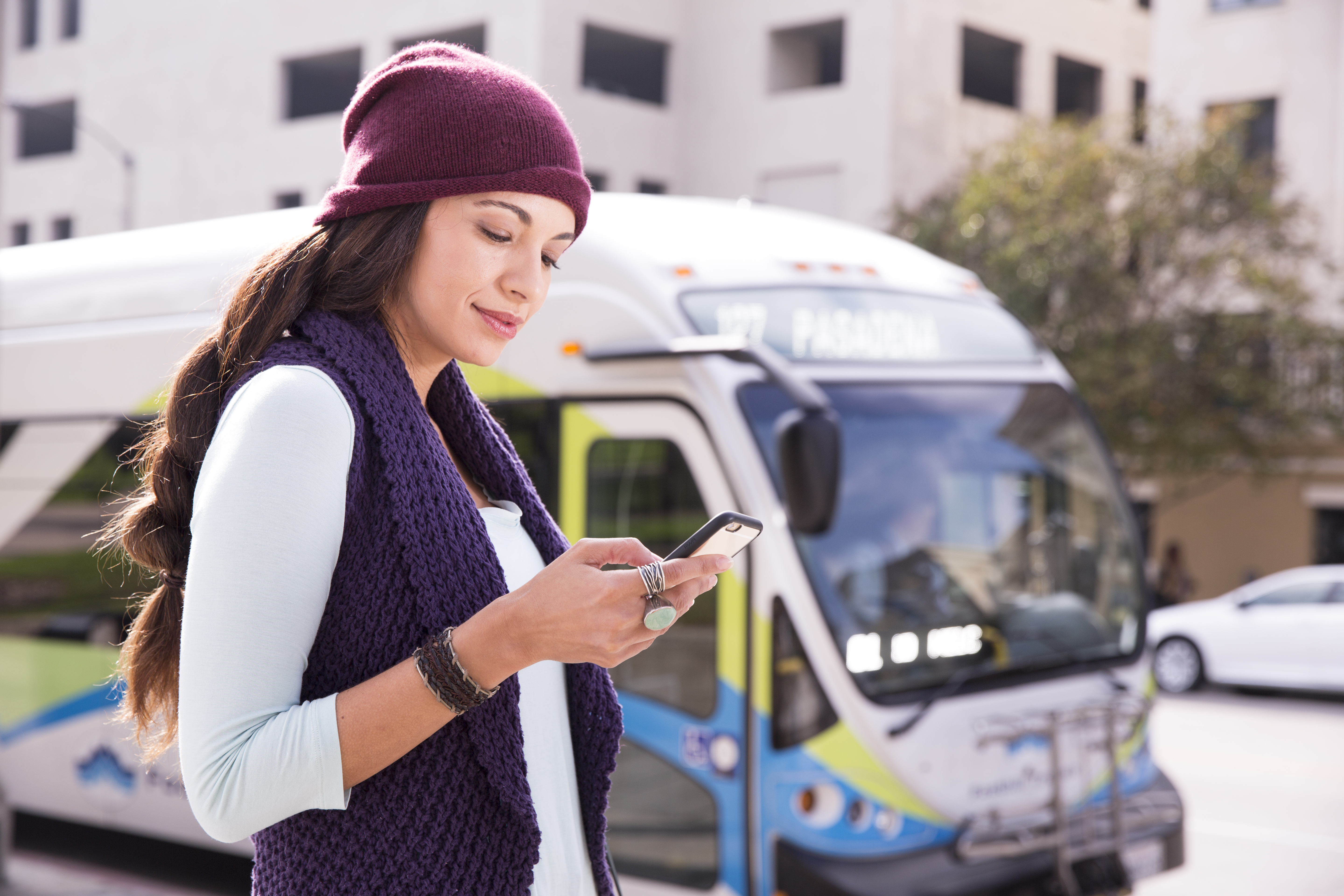 customer looks at phone with bus in the background
