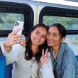 Two customers share a smiling selfie on board a bus.