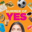 The words "Summer of Yes" are on a bright background above the top of a person's head -- the person is looking to the side and up at the objects surrounding the words, as follows: flip flops, an iced drink, a bike, a grocery shopping bag, a taco, a soccer ball, sunscreen, sunglasses, a sun hat, and sushi