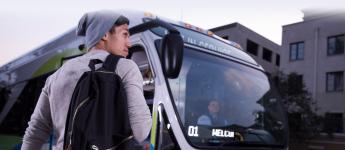 a customer with a backpack and a beanie boards a bus