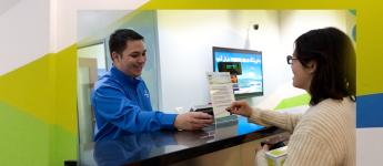 A customer service representative helps a customer in a transit store.