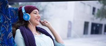 image: customer laughs while wearing headphones on a bus 