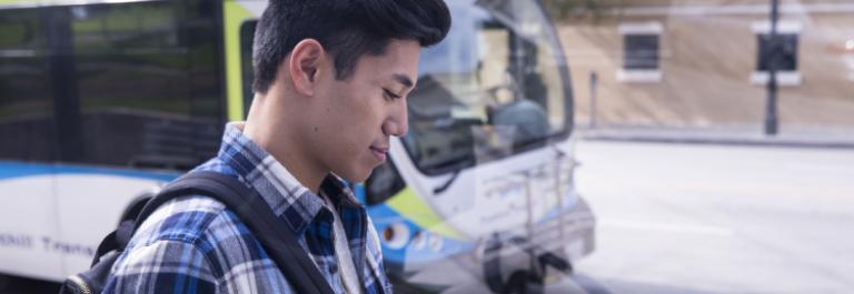 customer looks at phone in front of bus