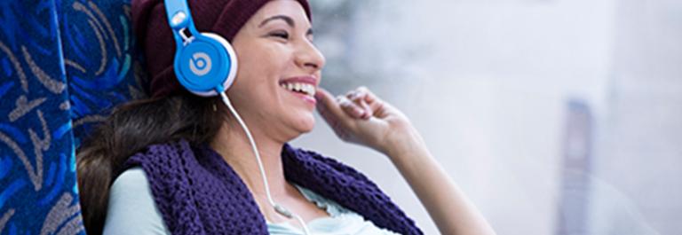 image: customer laughs while wearing headphones on a bus 