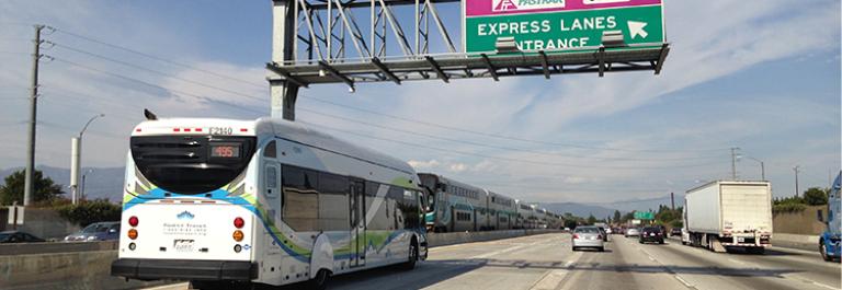 Line 495 bus on the 10 Freeway under a sign that says "Express Lanes Entrance"