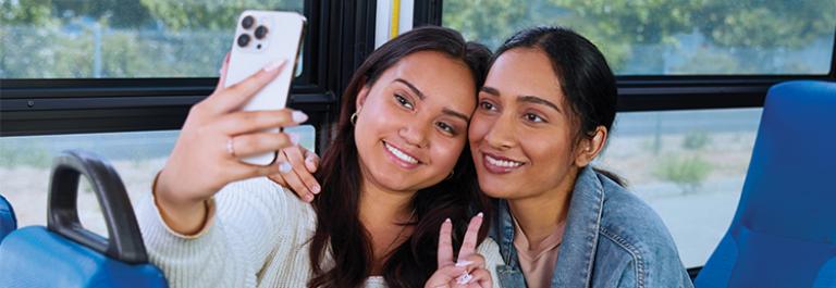 Two customers share a smiling selfie on board a bus.